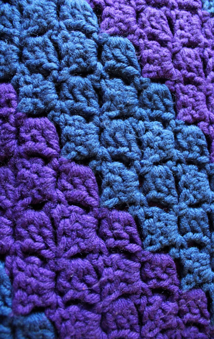 Close up of a crocheted blanket in purple and blue