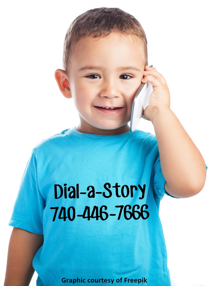 Little boy holding a phone with Dial A Story written on his shirt